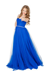 Studio shot young girl in elegant blue dress pointing finger at
