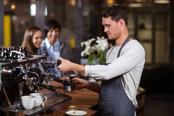 Barista making hot milk with coffee machine