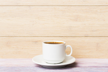 Cup of coffee over light wooden background
