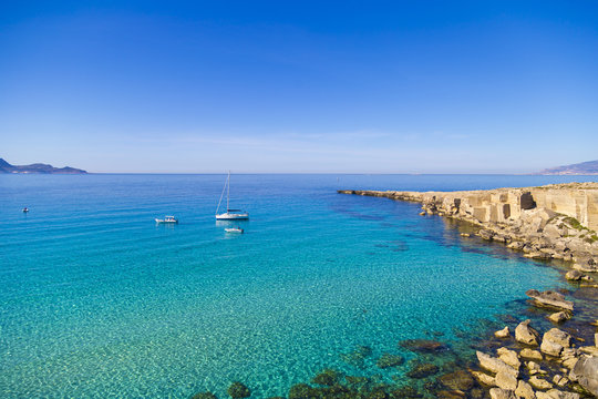 Azure lagoon called Cala Rossa with yachts moored on Favignana island in Sicily, Italy