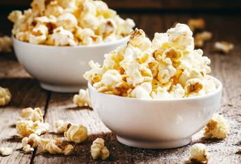 Sweet popcorn in white bowls, vintage wooden background, selecti