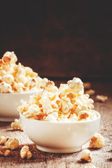 Sweet popcorn in white bowls, vintage wooden background, selecti