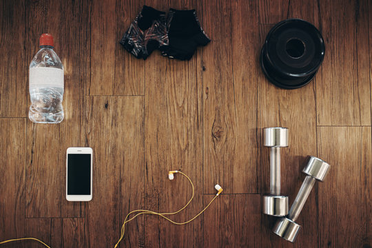 Fitness equipment accesories on wooden background, view above