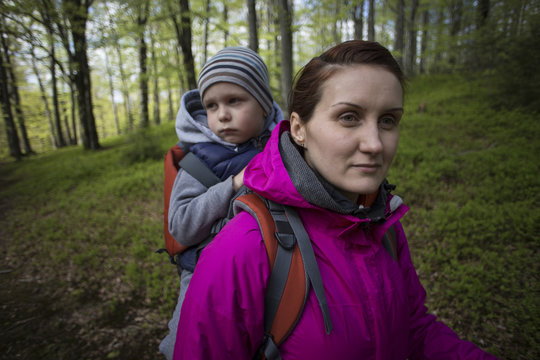 Mom walks in the forest with a child, a child in the children carry.