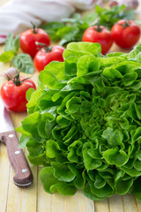 Fresh lettuce, tomato, basil and garlic for a light summer salad on a wooden surface, selective focus