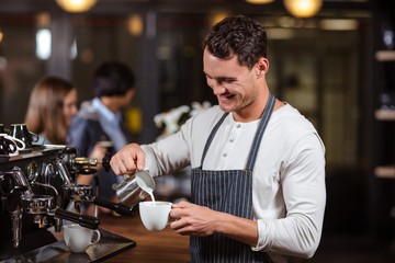 Smiling barista preparing cappuccino