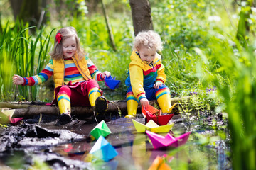 Kids playing with colorful paper boats in a park
