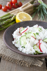 Risotto with fresh cucumber and radishes around fresh green asparagus spears