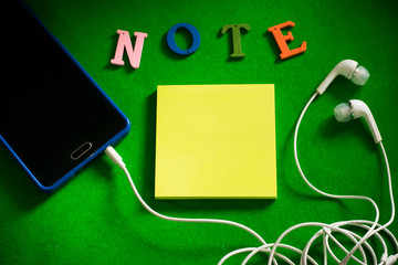 Notepaper and mobile phone with earphones.