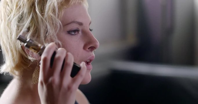 Close up of woman using an electronic cigarette in an urban loft.  Hand-held camera, profile view recorded at 60fps.