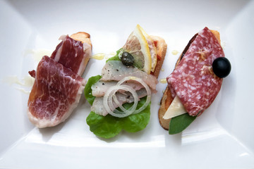 Mix of different snacks and appetizers. Spanish tapas on a black stone background.  Top view