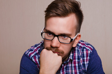 Man in dreams. Guy thinking. Portrait of man in glasses with a beard and mustache with his head propped on his hand
