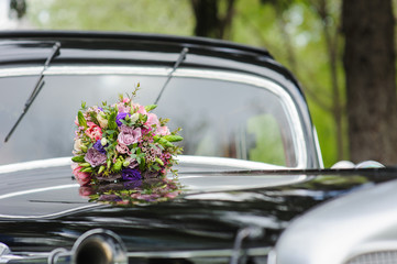 Bouquet of flowers on hood retro wedding car