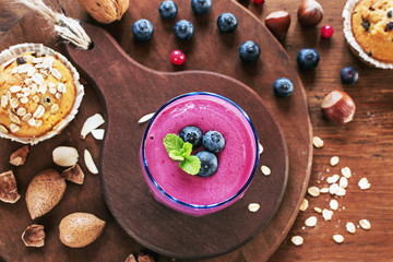 Breakfast with fresh smoothie,nuts,almond,hazelnuts and oatmeal muffins on dark wooden table. Rustic style.Top view. selective focus.