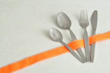 Cutlery displayed on a white background with an orange ribbon