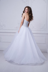 Fototapeta premium Young beautiful bride standing in antique interior ornamental design done with a moldings. Studio shot