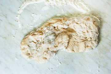 Kneading dough on white table, top view