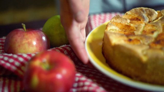 Man puts dish with freshly baked apple pie on table. Traditional american apple pie on kitchen table. Closeup. Autumn dessert. Cooked sweet food