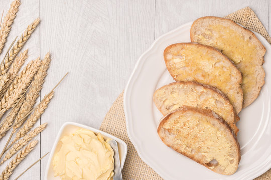 Fresh bread, wheat spike and homemade butter on wooden background