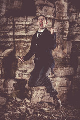 Fototapeta na wymiar Emotional jumping businessman on the night rocks background.