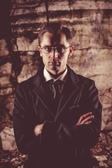 Businessman in black suit and tie on the dark rocks background.