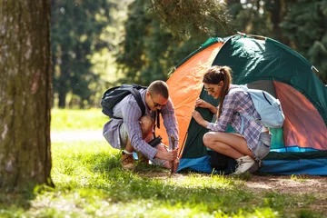 Fototapete Camping Junge Camper bauen das Zelt am Wald auf.