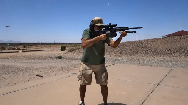 A man shoots his AR15 automatic weapon at a shooting range in the desert.  	