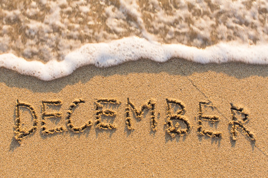 December - word drawn on the sand beach with the soft wave. Months series of 12 pictures.