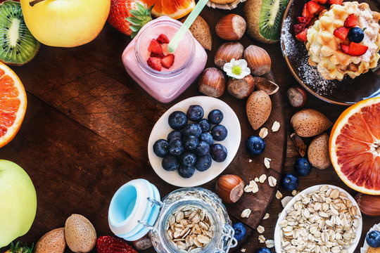 Health and colorful breakfast - with oat flakes, waffles, muffins,almond,hazelnuts,various fruits, berries and milk on old wooden table. Health food concept  .Top view.