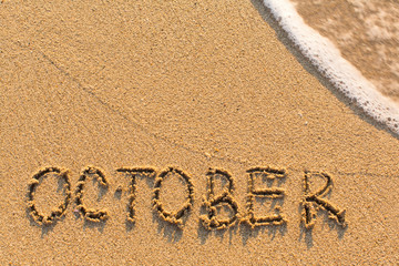 Fototapeta premium October - word drawn on the sand beach with the soft wave. Months series of 12 pictures.
