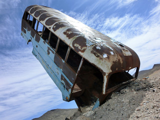 Vintage old rusty bus sticking out of the desert soil into the sky - landscape color photo