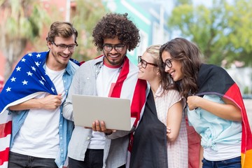 Friends holding national flag and using laptop