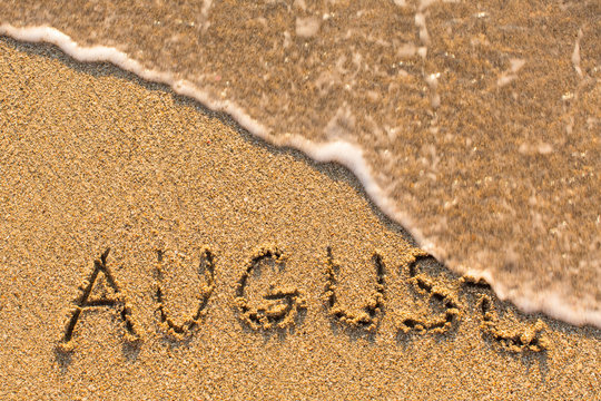 August - word drawn on the sand beach with the soft wave. Months series of 12 pictures.