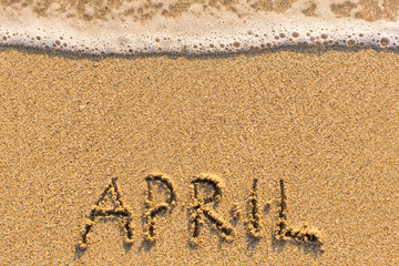 April - word drawn on the sand beach with the soft wave. Months series of 12 pictures.