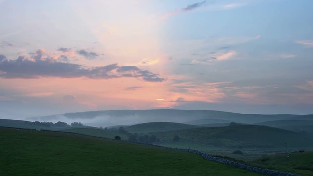 Time lapse of sunrise in Ribblesdale, Yorkshire Dales. Sheep grazing in the foreground. Zoom in and pan right.