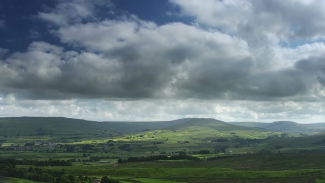 Time lapse of partly cloudy day.  Patches of sunlight sweeps across the scenery.