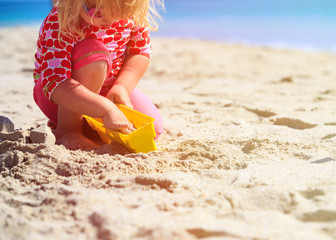 little girl play with toys on beach
