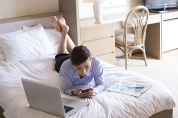 Obraz premium Women have to check the smartphone in a prone position on the bed