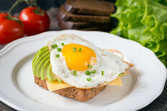 Sunny side up egg, avocado and cheese on whole grain toast for healthy breakfast