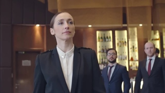 Businesswoman walking in front of her male colleagues in the hotel restaurant