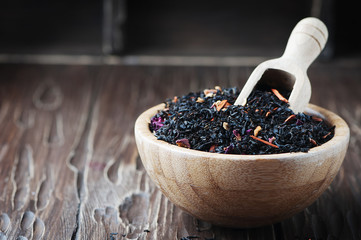 Delicious black tea with petals on the wooden table