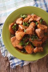 Adobo Chicken with herbs close-up on a plate.  vertical top view
