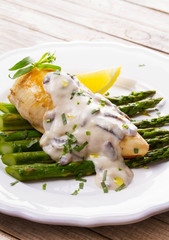 Fried chicken breast on asparagus with tarragon and mushroom sauce