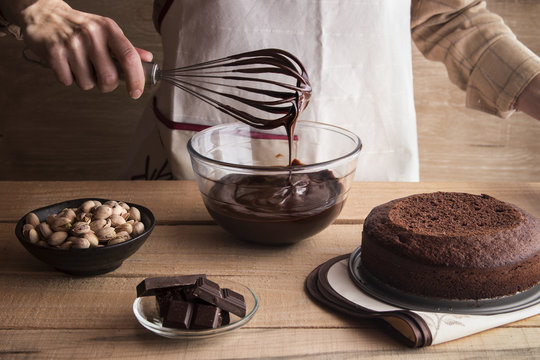 Woman cooking dark chocolate cake with ganache and pistachios