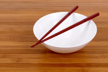 White empty rice bowl dish with wooden chopsticks on a bamboo wood board background photo