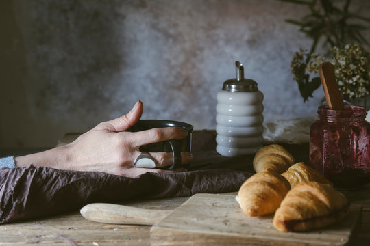 Woman drinking a cup of coffee with croissants