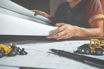 Creative architect projecting on the big drawings in the dark lo