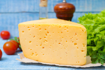 Tilsit Tilsiter cheese of the semi-hard cheese with vegetables on a wooden background