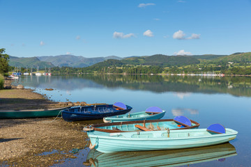 Rowing boats for hire for pleasure and leisure by beautiful lake and mountains calm still day    