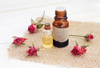 Fototapeta na wymiar Rose essential oils. Bottles of oil, dried rosebuds. Floral aromatherapy scent and skincare. 